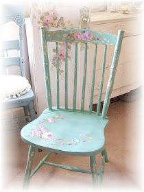 a blue chair with flowers painted on the back and seat is next to a dresser