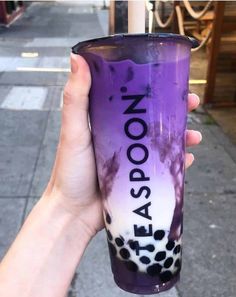 a person holding up a purple cup with the words teaspoon painted on it