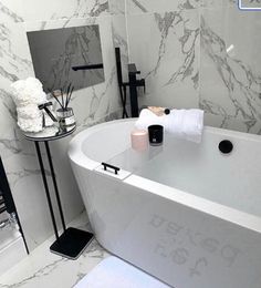 a white bath tub sitting in a bathroom next to a sink and toilet paper roll