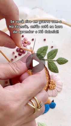 a woman is working on an embroidered piece with flowers and leaves in the background, while another person holds a pair of scissors