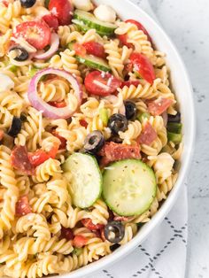 a white bowl filled with pasta salad on top of a table next to a napkin