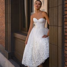 a woman in a white dress leaning against a window