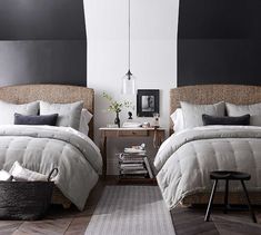 two beds in a room with black and white walls, one has a basket on the floor