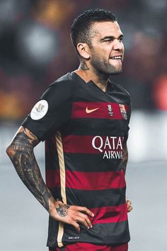 a man with tattoos on his arms and chest wearing a black and red striped shirt