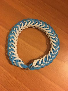 a blue and white braided bracelet sitting on top of a wooden table