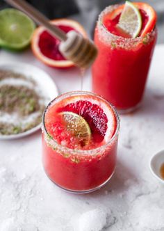 two glasses filled with blood orange margaritas and garnished with lime