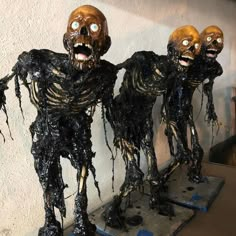 three fake human heads are on display in front of a white wall with black paint