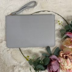 a gray purse sitting on top of a white blanket next to flowers