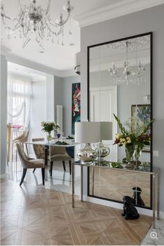 a living room filled with furniture and a chandelier hanging from the ceiling next to a mirror