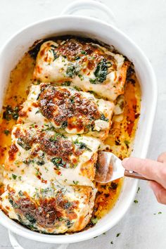 someone is spooning some food out of a casserole dish with cheese and spinach