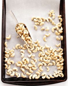 a pan filled with cashews on top of a baking sheet next to a spatula