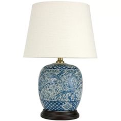 a blue and white vase with a light on it's side next to a lamp