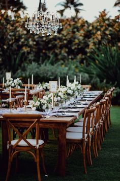 an outdoor dining table set up with white flowers and greenery for a wedding reception