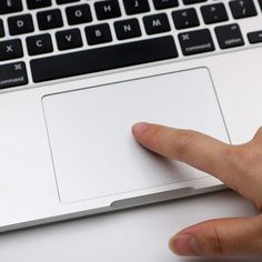 a person's finger on the keyboard of a laptop