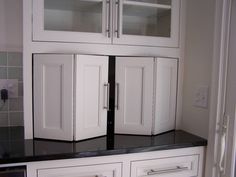 a kitchen with white cupboards and black counter tops in the middle of the room