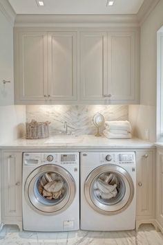 a washer and dryer in a white laundry room with marble counter tops on the floor