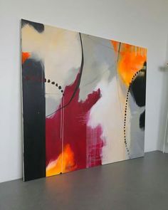 an abstract painting is displayed on the wall in a room with white walls and grey flooring