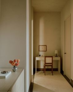 a room with a table, chair and vase on the floor next to a door