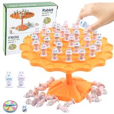 an orange plastic toy with lots of toys in front of it and a hand reaching for the top