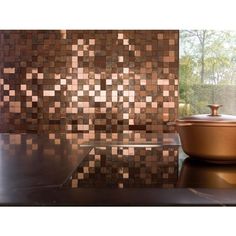 a bowl sitting on top of a counter next to a wall covered in brown tiles