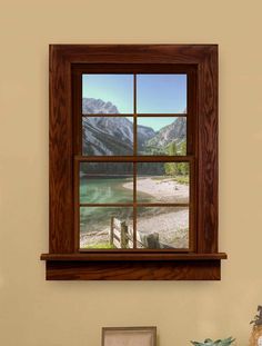 an open window with mountains in the background and a lake below it is framed by a wooden frame