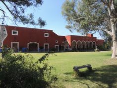 a large red building sitting next to a lush green park filled with lots of trees