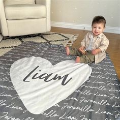 a baby sitting on the floor with a blanket that says i am