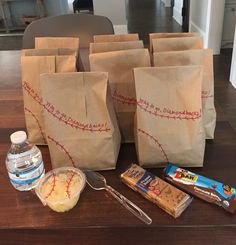 several brown bags sitting on top of a wooden table next to some snacks and water