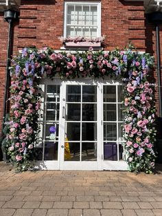 a brick building with flowers growing over the front door and windows on either side of it