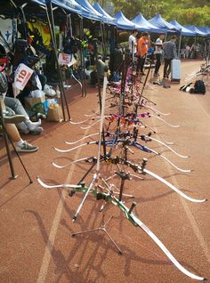 many skis are lined up on the ground in front of tents with people standing around them