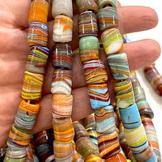 a hand holding several multicolored glass beads