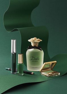 an assortment of cosmetics and perfume bottles sitting on a green surface