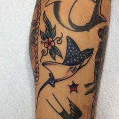 a man's leg with tattoos on it, including an anchor and other items