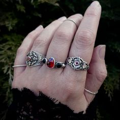 a woman's hand with three different rings on it, including one red and one black