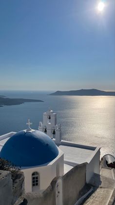 the sun shines brightly over an ocean and whitewashed buildings with blue roof tops