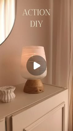 a white lamp sitting on top of a wooden dresser next to a mirror with the words action diy