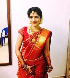 a woman in a red and gold saree is posing for the camera with her hands on her hips