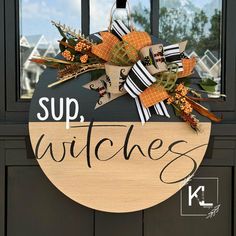 a wooden sign that says sup witches hanging on a door with ribbon and pumpkins