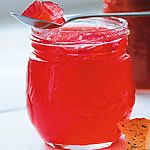 a jar filled with red liquid next to a piece of bread