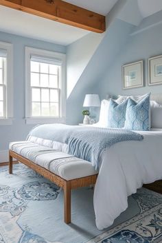 a bedroom with blue walls, white bedding and two windows on the side of the room