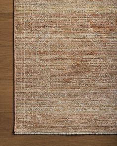 an area rug with brown and tan colors on top of a wooden floor next to a plant