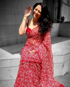 a woman in a red dress waves to the side with her hand on her hip