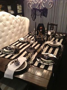 a dining room table set with black and white striped place settings, silverware and candlesticks