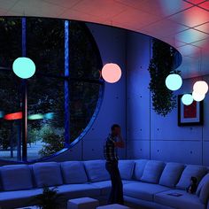 a man is standing in front of a large couch with lights hanging from the ceiling