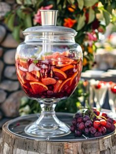 a glass jar filled with fruit sitting on top of a wooden barrel next to grapes