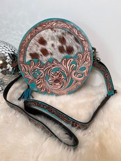 "Custom branded Turquoise and Cowhide Tooled Leather Round Crossbody purse These gorgeous round crossbody purses are made of genuine leather, pebble leather or distressed/waxed leather back and strap, tooled leather details on front and cow/goat hide Bag measures approx 10\" diameter and a 30\" purse drop fully expanded, adjustable to smaller size, we add your custom initials or farm/cow brand Can be custom branded, see our videos for actual brand appearance  All cowhide and leather products may Western Bags, Canteen Purse, Round Western Purse, Round Tooled Leather Purse, Leather And Cowhide Purses, Western Style Crossbody Bags For Western-themed Events, Western Crossbody Purse, Western Dog Collars, Circle Purse