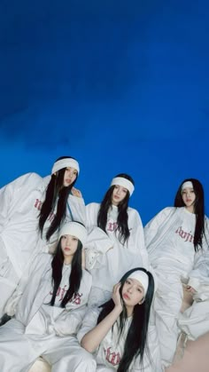 four young women in white outfits sitting on the ground