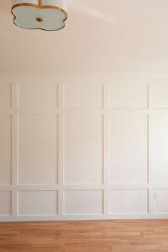 an empty room with white walls and wood flooring is pictured in this image, there are two lamps on the ceiling