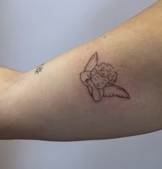 a woman's arm with a small tattoo of an angel holding a star on it