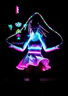 a woman with neon lights on her body and hands is standing in the dark,